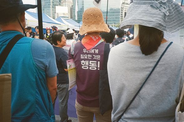 927기후정의행동 행진에 참여한 사람. 보라색 조끼 등쪽에 '우리에게 필요한 것은 행동!'이라고 적혀있다.