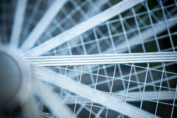Das Bild zeigt eine Nahaufnahme von metallenen Gitterstufen einer Spindeltreppe.