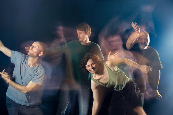 an artistic photo taken for my partner's event "Dancing Meditation". a dark blue image shows four people dancing in long exposure leaving streaks of colour and faint figures