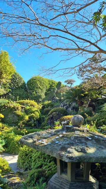 An old photo I took on another bright sunny day, in beautiful Chiran old town of Kagoshima on Kyushu, Japan - in the vicinity of old Chiran Samurai Residences Gardens. In the foreground of this garden scene, we see a moss-covered stone lantern that's also full of coins from well-wishers, while the background is a beautifully manicured Japanese borrowed-scenery garden basking in a clear blue afternoon sky.