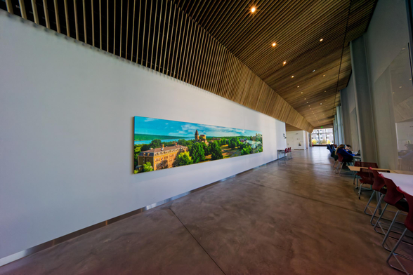 A long hallway seen sideways with a long video screen showing a famous cornell landscape.