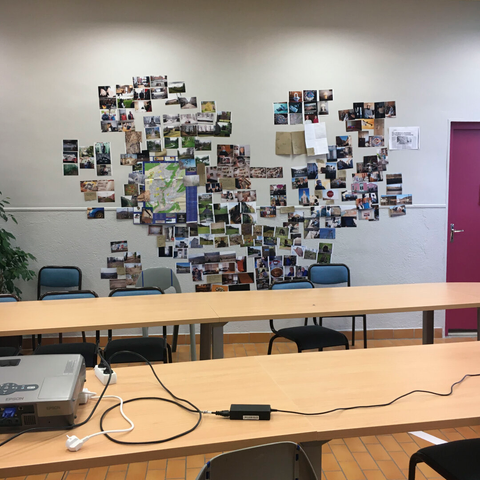 Salle de classe, atelier photo, beaucoup de petites photos collées au mur qui forment un coeur