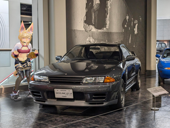 A grey nissan skyline gt-r sports car from the front with a happy person standing next to it