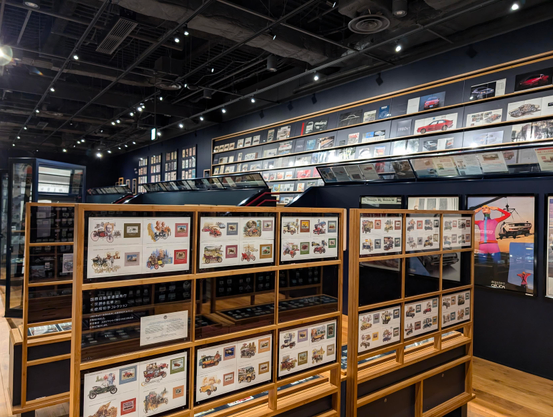 A big room full of displaycases with car-related prints in it