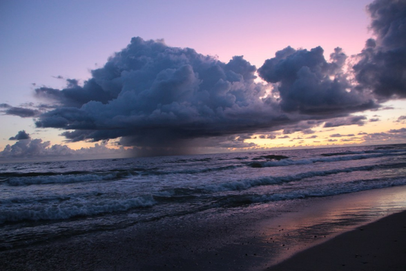 Abendstimmung. Eine Wolke regnet über dem Meer, nahe am Strand ab