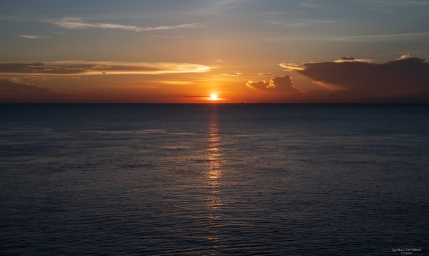 The setting sun is reflected in the sea. 
