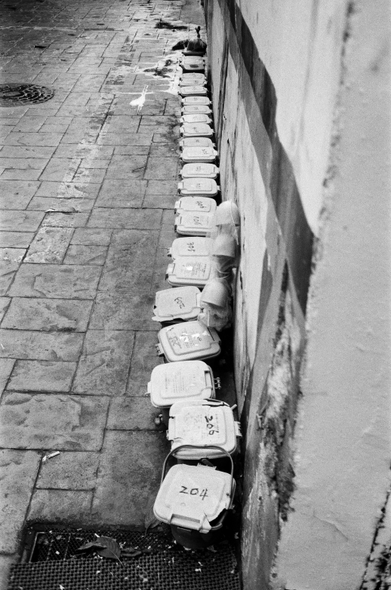 주택가 담벼락을 따라 작은 음식물쓰레기 통이 일렬로 길게 늘어서있다.