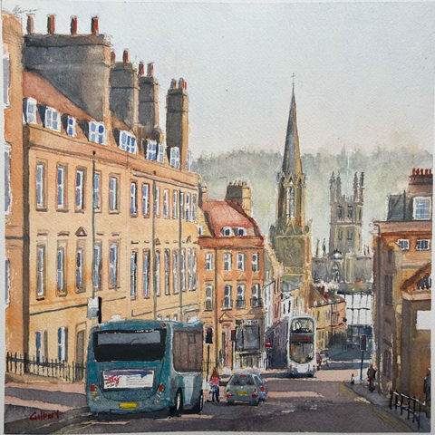 A watercolor painting depicting a street scene with buildings featuring classic architecture. A blue bus and a car are visible on the street, alongside pedestrians and a woman on a bicycle. In the middle a double decker bus drives towards us. In the background, a church steeple and additional buildings can be seen, with a distant hill behind.