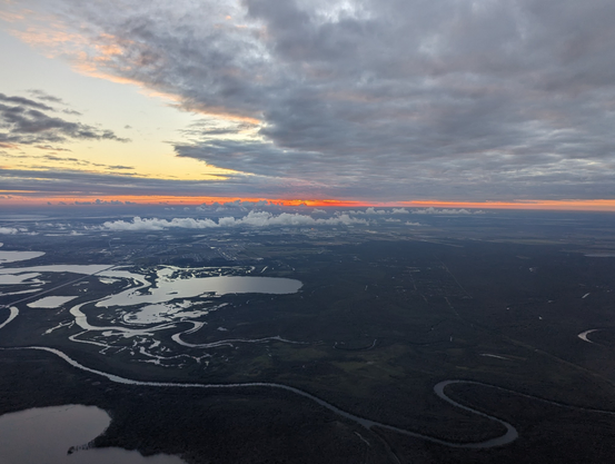 Sunset seen as a glowing red line between clouds and land. There's a break in the clouds to the left showing blue sky trending toward yellow.The land is an interesting mix of river and river delta.
Taken from airplane window while on approach into Houston, TX.