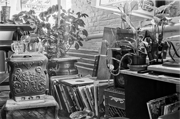 black and white photo still life of plants, records, and old stove in loft living space