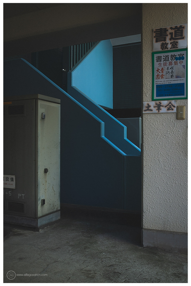 A blue staircase in Kinshicho, Tokyo. Light catches the edges of this blue concrete staircase. An electricity junction box is in the foreground. 
