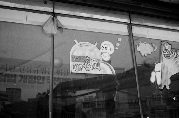 문닫은 휴대폰 매장 유리벽에 철 지난 옛날 스마트폰 광고가 붙어있다. “누구보다 빠르게! Galaxy S3”
