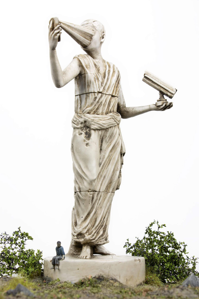 A large sculptural figure draped in flowing fabric, holding an object in one hand while using a cone-shaped item in the other.