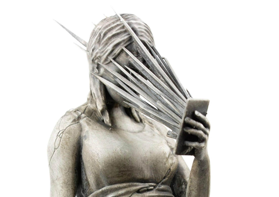 A silver sculpture depicting a figure with a phone, surrounded by sharp protrusions, symbolizing digital distraction or overwhelm.