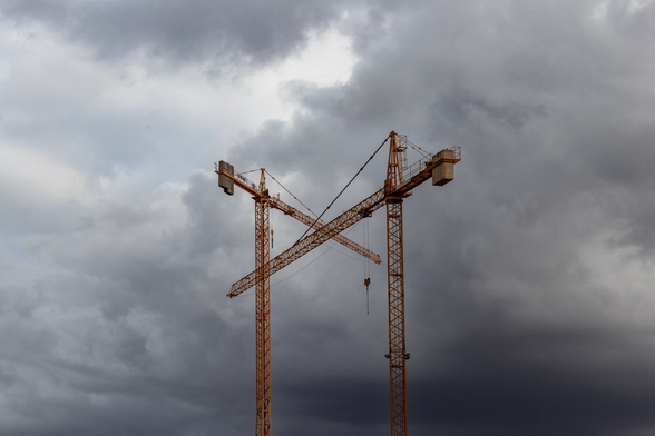 Español: se pueden ver dos grúas de la construcción cruzadas formando una especie de equis. Ambas con un cielo de nubes de tormenta alrededor.

English: You can see two construction cranes crossed, forming a sort of X. Both are surrounded by a sky of storm clouds.
