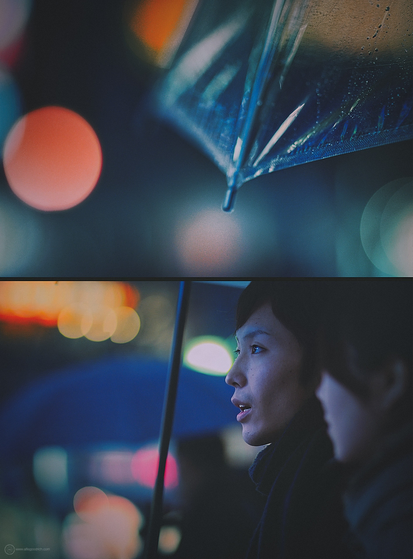 A couple under an umbrella in this night time shot from Shibuya, Tokyo, back in 2009. This is a diptych, with the upper frame of the two being a close up of the edge of the transparent umbrella. The lower frame focused on the man holding it. His partner is blurred out in the foreground.