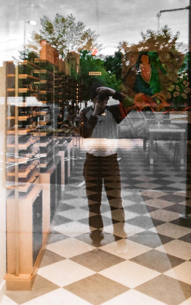 A color photo of the inside of shop and through a plate glass window in which you can easily see yours truly taking the picture as well as the trees in the background.