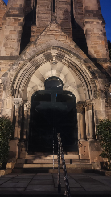 The main, double doors with Gothic carved arch above, for King's Church, illuminated at night