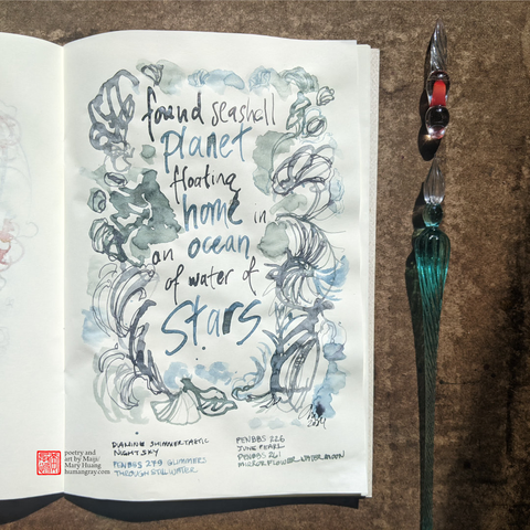 Photo of notebook next to two glass dip pens, one of which is just a tip. The page shows a handwritten haiku with words in glittering silver, pale blue and green tones, surrounded by swirling lines evoking the shapes of seashells and water. 
"found seashell planet
floating home in an ocean
of water of stars"
- Poetry and art by Maiji/Mary Huang, humangray.com
