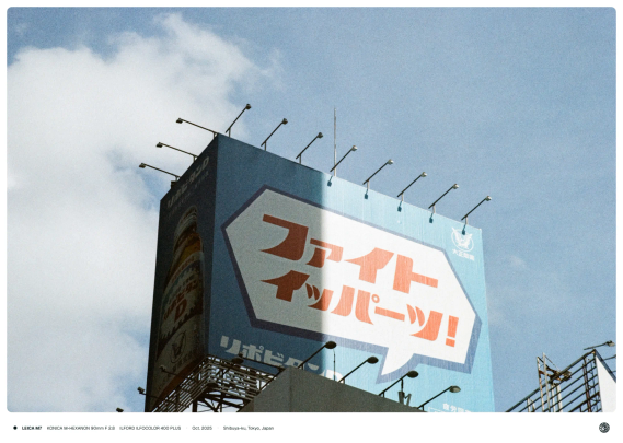 하늘색 리포비탄 광고판에 LED 전등이 나열되어 달려 있는 모습. 뒤로는 흰 구름과 맑은 하늘이, 광고판에는 앞 건물의 그림자가 걸쳐 있다.