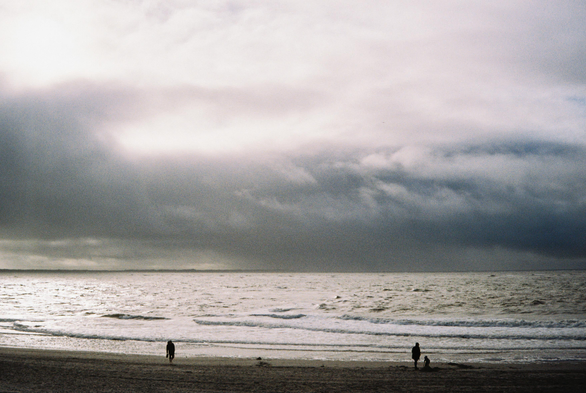 Analog color photo of a cloudy seascape in soft pastel tones with clear film grain. Three figures stand apart on the beach—one walking alone, two together near the water—while small waves roll toward the shore under heavy clouds and diffused light shimmering on the ocean. (Photo by me, CC BY 4.0, Kodak Gold 200, Minolta Riva Zoom Pico, early 1990s, minor edits on the scan)

Found an old Minolta Riva Zoom Pico point-and-shoot at a flea market a few weeks ago and took it to the sea.