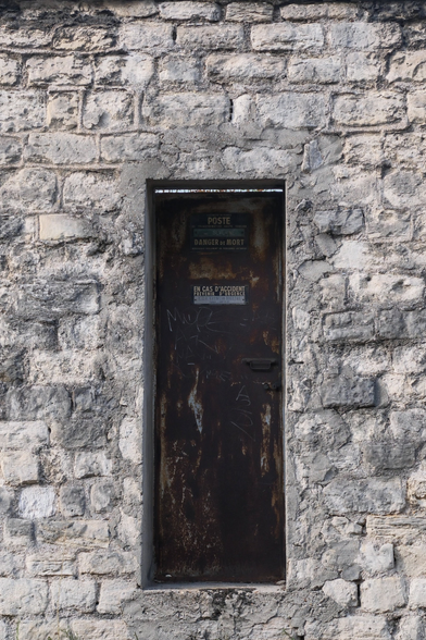 A small rusted door in a wall made of stones