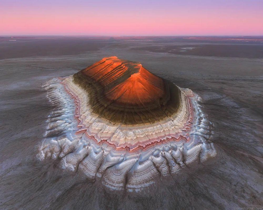 A mountain rises from an old seabed in layers of colors