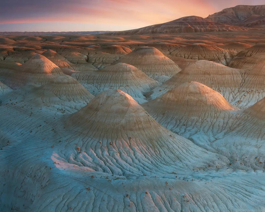 Mounds from the old ocean floor on pale blue rising to brown set against a sunset