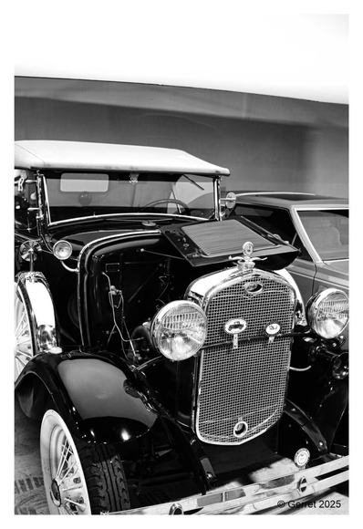Black and white photo of a vintage car with a distinctive chrome grille and large round headlights. The car exudes a nostalgic, classic ambiance.