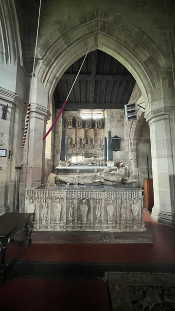 The interior of St Bartholomew's showing the tombs of local nobility in pale stone.  The bell ropes hanging from the belfry can be seen on the left of the picture.