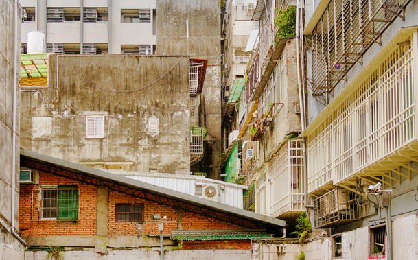 Residential facades with windows, balconies, ACs, and burglar bars.
