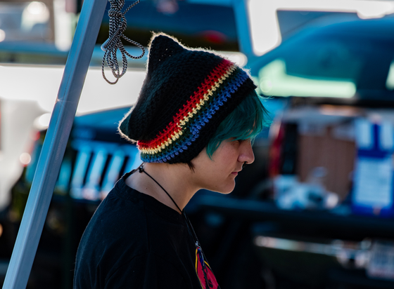 A profile photo of a young lady with a pull over cap with rings of color.  She also has colored her hair a kind of teal color.