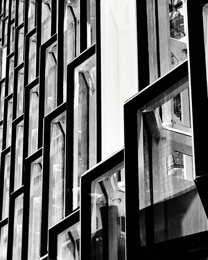 This black and white photograph captures the intricate geometric design of Harpa's facade in Reykjavik. The play of light and shadow across the glass panels creates a dynamic and bold visual effect, showcasing architectural elegance in monochrome.