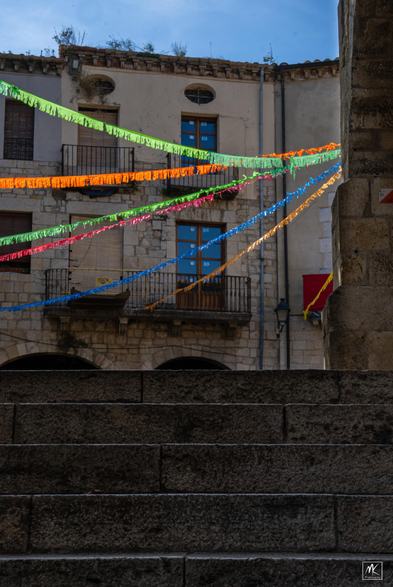 Color photo looking up stone steps that lead to a plaza with colorful streamers hanging.