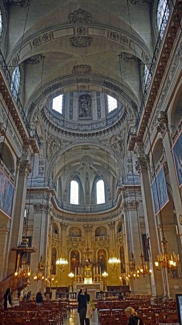 Photograph by Fenichel
A vertical slice of the interior of the chapel of the Church of Saint-Paul-Saint-Louis, historical in its architecture, transitioning from Gothic to Baroque. 

Here is the view looking up from behind the pews up to the pulpit (bottom 1/5) and then seeing upward to lavish carvings, pillars, windows, and more-Baroque than Gothic arches. Sunlight is streaming through the windows, so one can see the details of intricate carvings and artistic flourishes.