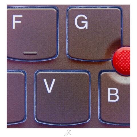 Square close-up of a laptop keyboard. Two rows of keys can be seen. The keyboard is dark silver-gray and backlit. We see the upper row with the "F" and "G" key. The "F" key has a haptic marker at the bottom. Below there are three keys. The leftmost and the rightmost can just be seen in half. The center key is the "V", right to it the "B". The right bottom edge of the "G" and the top center of the "B" have a rounded recess and are adjacent to a red round knob with tiny nubs on its surface.

AI disclaimer: Using my work, its meta data, written or derived description to create media with or train AI based systems is prohibited.