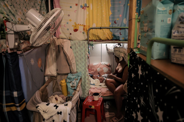 Marian Duhapa, a migrant worker from the Philippines, dresses her three-month-old baby.