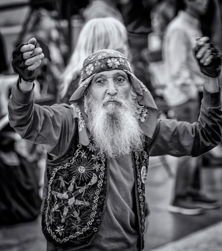 Older man with beard wearing do-rag dances in front of a band at a free concert in San Francisco.
