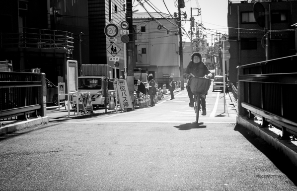 Dona amb bicicleta a punt de travessar un pont