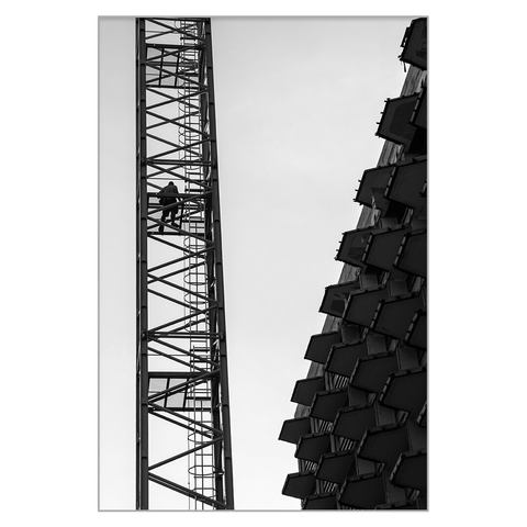 On the left side of the black and white image, you can see the body of a crane, with a man climbing up on it. On the right side of the image, there is a building under construction, its protruding balconies drawing an interesting pattern in the dawn sky. The mass of the building and the airiness of the crane with the man climbing up in the middle - I liked the contrast.