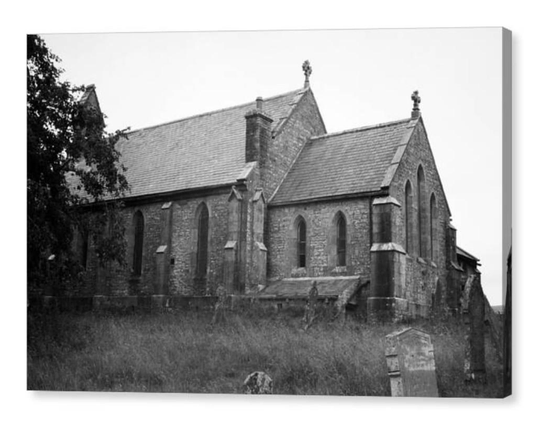 Gloomy black and white film photograph of an old Victorian church.  Gravestones can be seen in the foreground.
