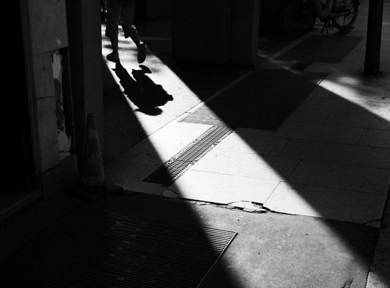 A man walks away in a sliver of light among shadows.
