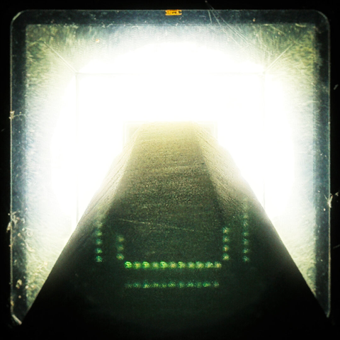 A view from straight up an outdoor lamppost reveals a bright light filling most of the frame.