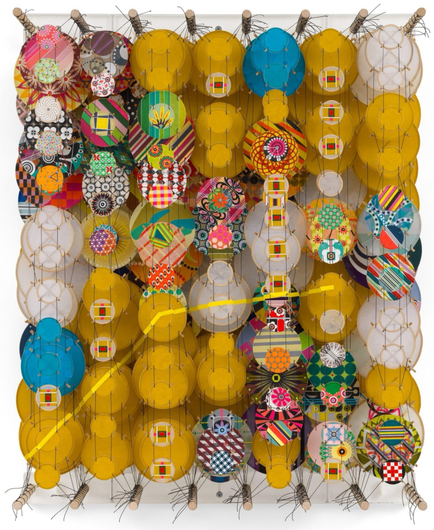 an abstract artwork by Jacob Hashimoto made from twine and numerous colorful, patterned paper discs installed in rows for a layered effect