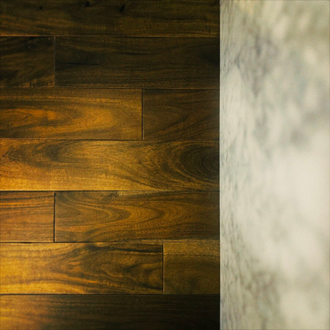 Deep brown horizontal wooden slats filling two-thirds of frame left lead to bright white marble on the final third at frame right.