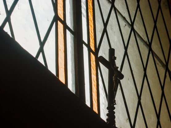 a stained glass window in a chapel with a small crucifix placed before it