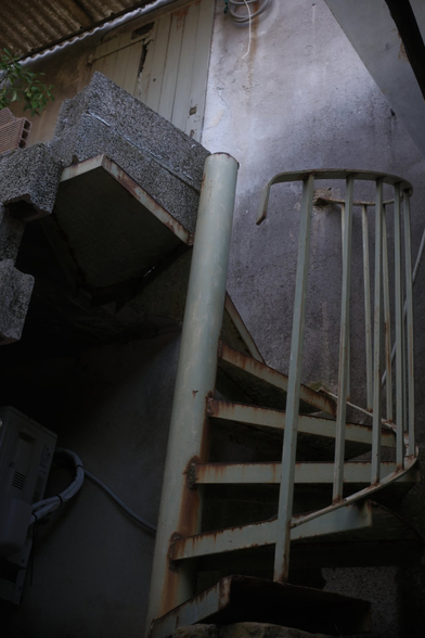 A low angle photo of an old metallic very pale and rusty green stair case