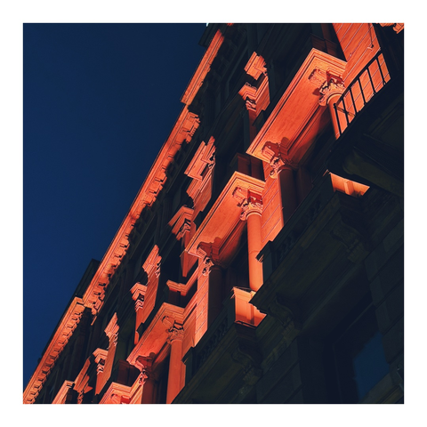 Blick von unten auf eine angestrahlte stark gegliederte Hausfassade