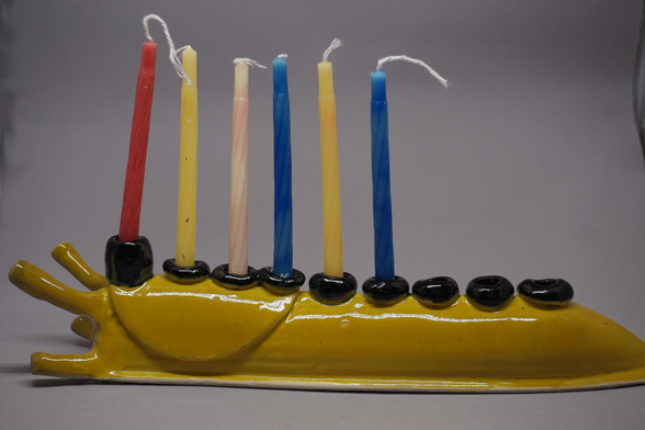 Photo of a giant ceramic banana slug with hanukkah candles down its back.