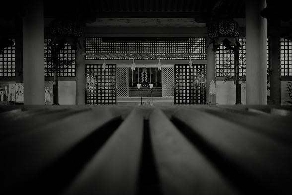 Photo of a Shinto shrine  in black/white. Playing with perspective. At the button of the picture wooden bars are shown.